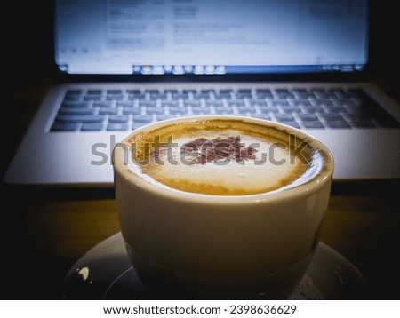 cup of cappuccino on laptop background, coffee foam, remote work, IT specialists
