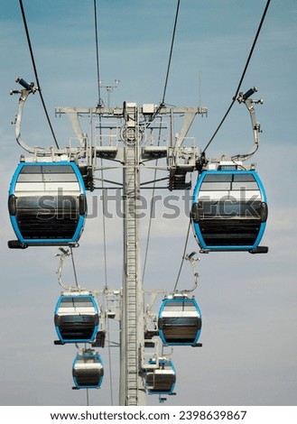 Cable car, suspended carriages, rise up the mountain, against the background of the blue sky

