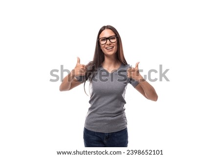 young positive brunette woman with glasses in a gray t-shirt with a mockup on a white background with copy space