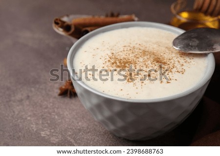 Delicious semolina pudding with cinnamon in bowl and spoon on brown table, closeup. Space for text Royalty-Free Stock Photo #2398688763