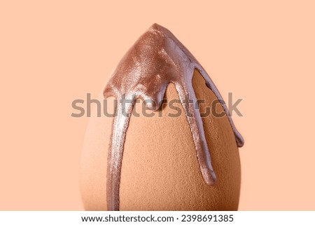 Closeup photography of beauty blender with dripping bronzer on it.Neutral beige background,large banner with copy space.