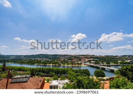 A view of Coimbra City under a clear sky, with Mondego River, trees, and buildings. Landscape background and wallpaper.