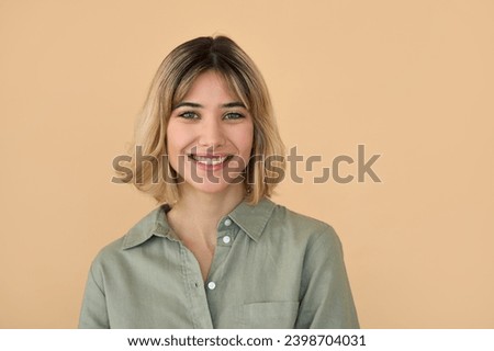 Smiling pretty gen z blonde young woman, cute happy 20s european student girl with short blond hair wearing khaki shirt looking at camera standing isolated on beige background. Close up portrait. Royalty-Free Stock Photo #2398704031