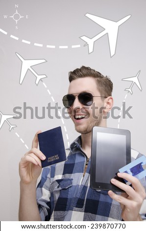 Young adult man books traveling ticket via tablet holding credit card and passport in his hands. Traveling concept with graphic pictures of airplanes 