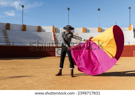 Hispanic matador dancing on sandy arena Royalty-Free Stock Photo #2398717831