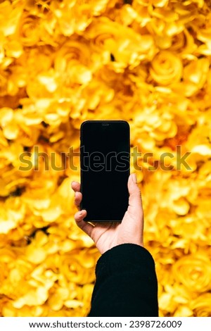 Body part of crop anonymous female taking picture on smartphone of bunch of fresh bright yellow Roses and Hydrangea Rodeo Cerise with Paeonia suffruticosa blooming