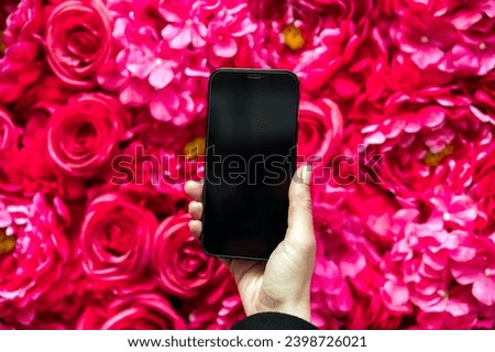 Body part of crop anonymous female taking picture on smartphone of bunch of fresh bright pink Roses and Hydrangea Rodeo Cerise with Paeonia suffruticosa blooming