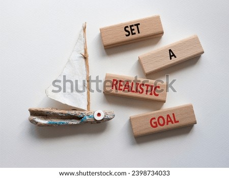 Set a realistic goal symbol. Concept words Set a realistic goal on wooden blocks. Beautiful white background with boat. Business and Set a realistic goal concept. Copy space.