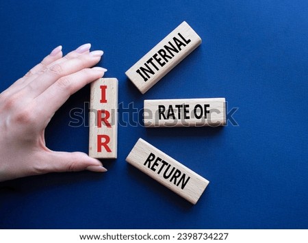 IRR - Internal Rate of Return symbol. Concept word IRR on wooden cubes. Businessman hand. Beautiful deep blue background. Business and IRR concept. Copy space.