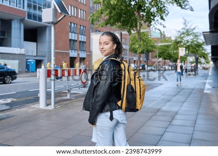 Portrait of teenage high school student girl with backpack on city street Royalty-Free Stock Photo #2398743999