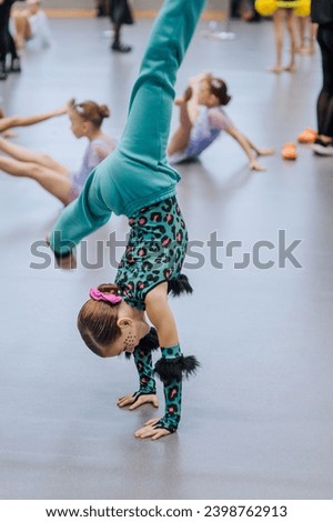 Girl athlete, child, gymnast in a tracksuit doing an exercise, a gymnastic element in the gym, training before a competition. Photography, sports.