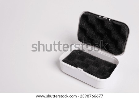 White open box lined with black sponge inside, isolated on a white background. Black mini pouch bag for storing small things. Inside of the protection bag. Copy space