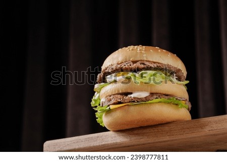 perfect tasty big double burger on wooden table on brown background, bottom view Royalty-Free Stock Photo #2398777811