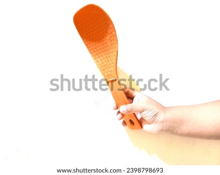 girl's hand holding a plastic spatula on a white background