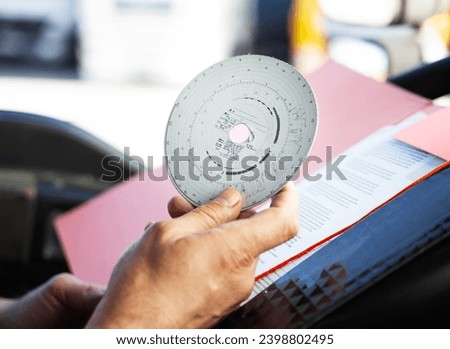Closeup shot of truck driver holding analog tachograph disc in hands  Royalty-Free Stock Photo #2398802495