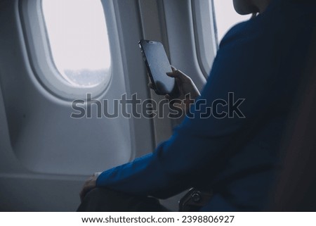 Young Asian business woman talking on smartphone, businesswoman working while flying at plane, Young woman using the internet at airplane, Air travel, long flight. Royalty-Free Stock Photo #2398806927