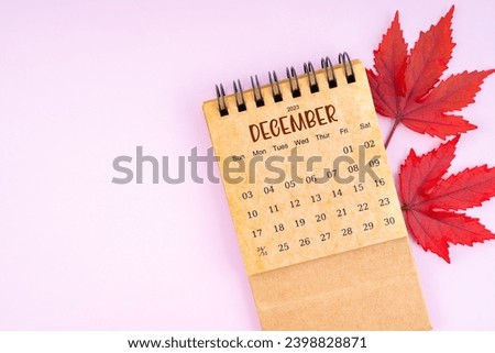 December 2023 monthly calendar and fall leaves on pink color background. Position with copy space.