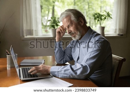 First steps in using computer. Thoughtful mature man study pc on retirement sit by desk look at laptop think on next step read guide for beginners on screen. Concerned old male ponder on news in email Royalty-Free Stock Photo #2398833749