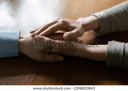 Holding hands. Affectionate middle aged woman touching mature man hand share hope believe in good. Loving elderly female express devotion emotional support to male spouse friend partner. Close up view Royalty-Free Stock Photo #2398833843