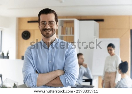 Portrait of smiling successful Caucasian male employee in glasses feel optimistic excited at workplace. Happy millennial businessman show leadership and confidence in office. Recruitment concept.