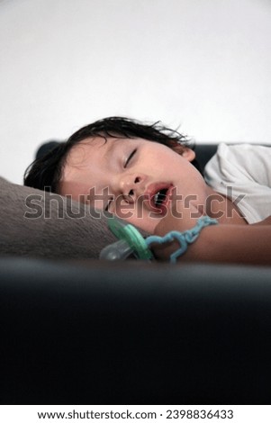 
Hong Kong, Asia - 01 31 2010 : Interior photo view of a young eurasian asian handsome good looking male 3 years old baby sleepy boy having an afternoon sleeping nap rest resting during the day