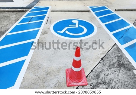 Blue rectangle handicapped sign with wheelchair and orange traffic cone. Handicapped symbol white on blue square frame and speed bump on a concrete road. To create convenience. Parking for wheelchair 