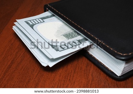 Closed diary with dollar banknotes inside Royalty-Free Stock Photo #2398881013