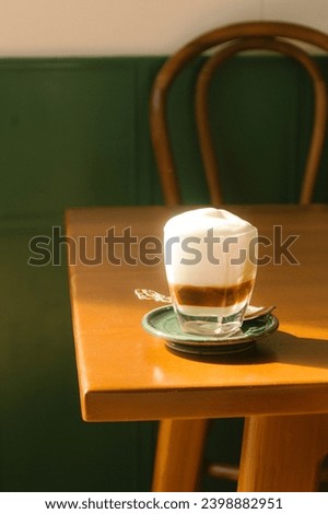 Coffee with milk in glass on the table with shadow and light make you feels warm and miss the taste of coffee in morning . Royalty-Free Stock Photo #2398882951