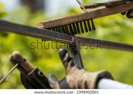 Welder cleans the welding surface using wire brush to remove residue flux and slug Royalty-Free Stock Photo #2398902001