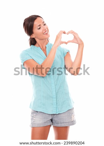 Pretty hispanic lady looking at a love sign while standing and smiling in white background