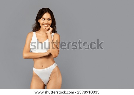 Smiling european slim millennial lady in white underwear with perfect body, look at copy space, isolated on gray studio background. Beauty care, weight loss and lifestyle, fit ad and offer Royalty-Free Stock Photo #2398910033