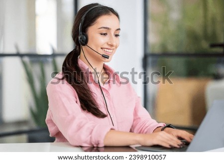 Positive pretty young european woman manager in headset typing on laptop, enjoy work in coworking office. Project, planning startup, business support, job service remotely