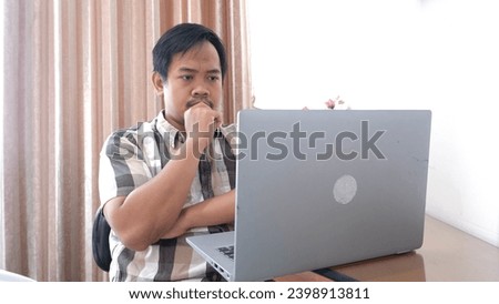 Southeast Asian man concentrates to analyze in front of his laptop 