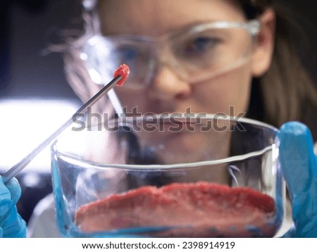 female scientific researcher observes a sample of cultured meat cultivated meat, cellular agriculture, synthetic meat production concept Royalty-Free Stock Photo #2398914919