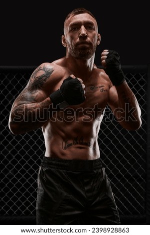Conceptual image of a kickboxer. A real fighter stands in the real cage of the octagon. The concept of mixed martial arts, kickboxing, sports schools. Mixed media Royalty-Free Stock Photo #2398928863