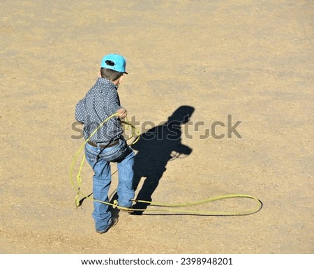 Young unidentified cowboy practicing with his lasso for when he is in a rodeo when he is older. 