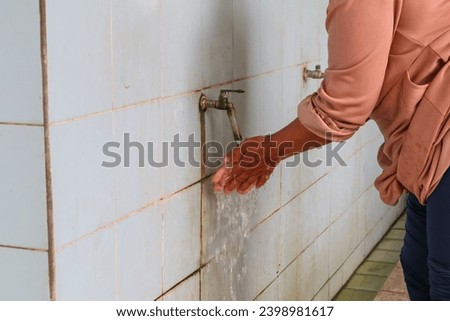 a woman washing her hands under a running tap