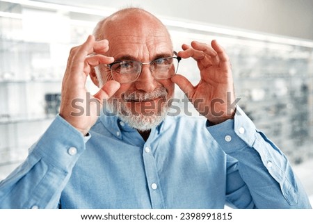 Mature man senior choosing optical glasses for himself in a professional store. Vision correction and ophthalmology. Royalty-Free Stock Photo #2398991815