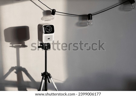 a white movie projector on
 on a tripod against a white wall