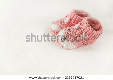 Pink knitted children's shoes on a white background with copy space. Pregnancy and motherhood concept, first birthday banner, handmade socks, baby warm clothes, handmade knitted socks, hobby. Royalty-Free Stock Photo #2399017021