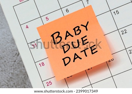 Baby due date written on a orange paper sticky note and stuck to a calendar background. Reminder concept. Royalty-Free Stock Photo #2399017349