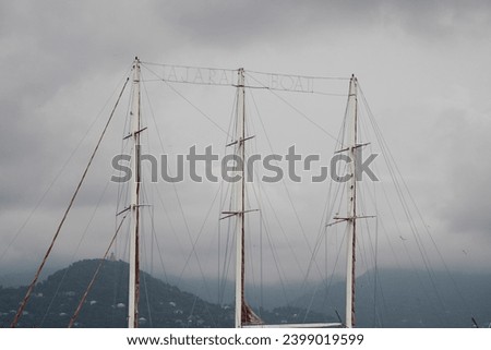 Lots of boat masts in a marina with cloudy sky background.