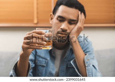 Health care alcoholism drunk, fatigue asian young man hand holding glass of whiskey, alone depressed male drink booze on sofa at home. Treatment of alcohol addiction, suffer abuse problem alcoholism. Royalty-Free Stock Photo #2399031645