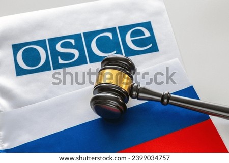 Warsaw, Poland - December 2023: The judge's gavel against the background of the Russian flag and the OSCE (Organization for Security and Co-operation in Europe) flag Royalty-Free Stock Photo #2399034757