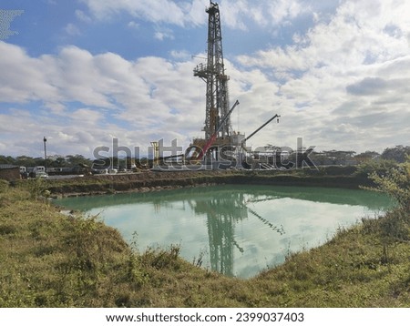 The drill site near the water body stands as a testament to the complexities of coexistence between industrial progress and environmental stewardship Royalty-Free Stock Photo #2399037403