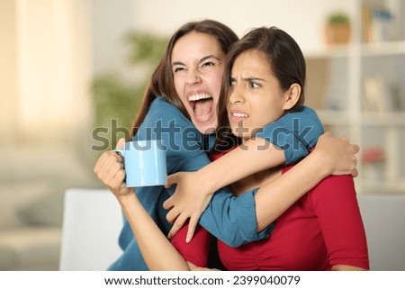Excited woman hugging to an upset friend at home Royalty-Free Stock Photo #2399040079