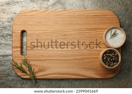 Wooden cutting board and spices on textured table, top view. Space for text