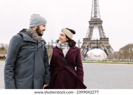 Lovely young european couple walking through paris. Two millennial people visiting Eiffel Tower during winter vacation. Love, european travel and holiday lifestyle concept.