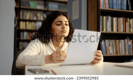 Portrait of upset young student got a bad grade on the exam and feeling upset sitting at desk at classroom Stressed curly girl failed exam and feeling worried about having problems in university Royalty-Free Stock Photo #2399052985