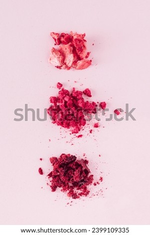 Smashed dehydrated fruits on the pastel pink background. Flat lay photography of dried strawberries, raspberries and cherries. Natural helalthy snack